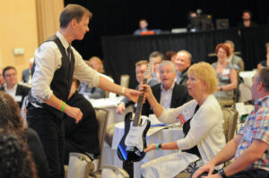 Mike gives guitar to audience member