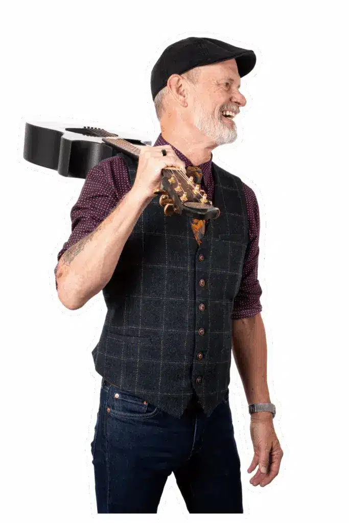 Mike Rayburn smiling with guitar, blending music, comedy, and strategy to inspire innovation and peak performance in keynote sessions